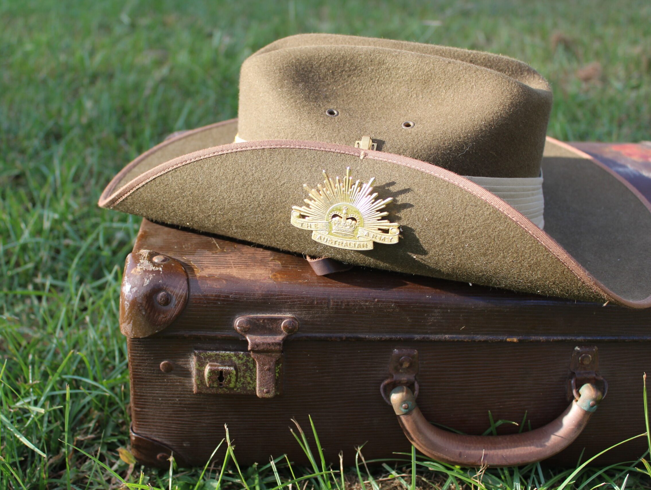 ANZAC hat resting on an old briefcase on green gass